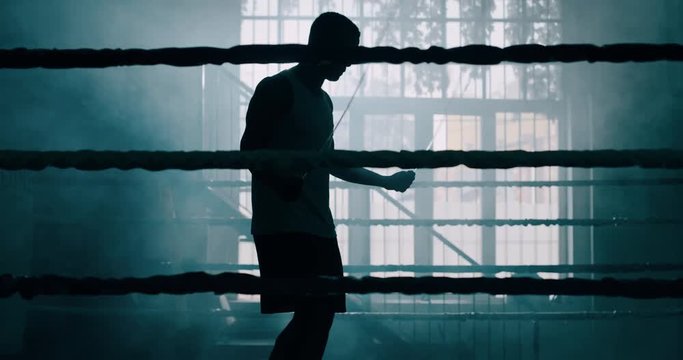 Cinematic slow motion shot of a professional young muscular african man is practicing shadow boxing work out in a ring. 