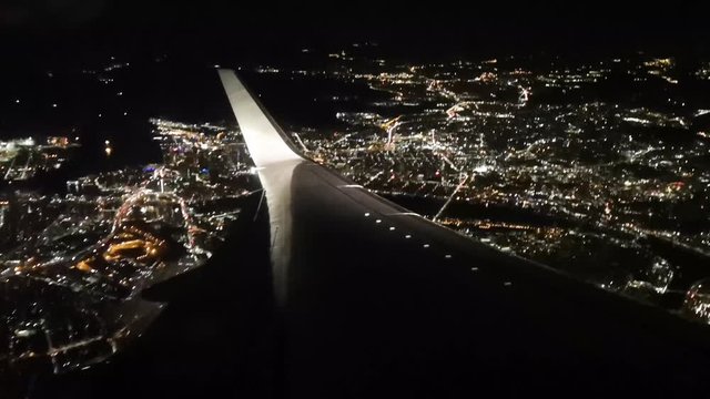 Windows seat. Airplane landing on the airport at night. Arriving aircraft. Flying.