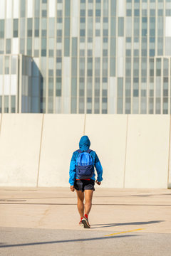 Rear view of senior sport man wearing hoodie and backpack walking away