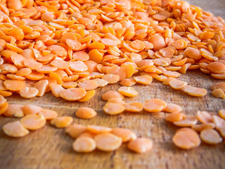 Close up of red lentils split uncooked on wooden surface