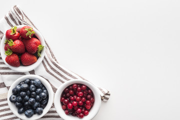 top view of sweet cranberries and blueberries, strawberries on bowls with towel