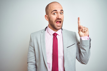 Young business man wearing suit and purple tie over isolated background pointing finger up with successful idea. Exited and happy. Number one.