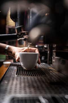Crop hands of man making coffee by automatic professional equipment in cafe