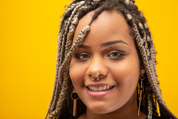 Beautiful young african american woman with dread hair on yellow background