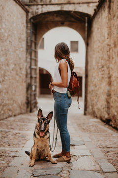 Cute german shepherd standing on cobblestone pavement with owner standing