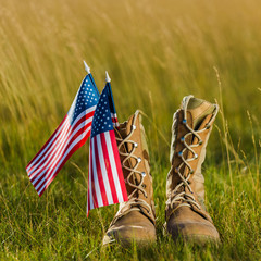 close up of military boots near american flag with stars and stripes on grass