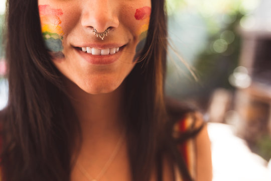 Brunette woman with LGBT symbol on face straightening hair