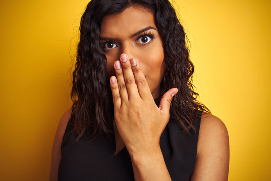 Transsexual transgender woman wearing black t-shirt over isolated yellow background cover mouth with hand shocked with shame for mistake, expression of fear, scared in silence, secret concept