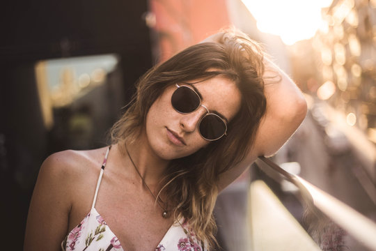 Attractive pensive model with long hair in summer dress on blurred background using sunglasses