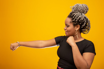 Beautiful side young african american woman with dread hair bringing punches in the air, showing...