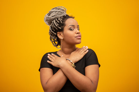 Beautiful young african american woman with dread hair on yellow background