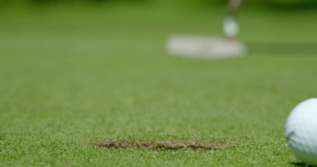 Rack Focus shot of a golf ball missing the cup, this golfer needs more coaching!