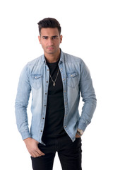 Young handsome man standing in studio shot, isolated on white, wearing denim shirt and black jeans
