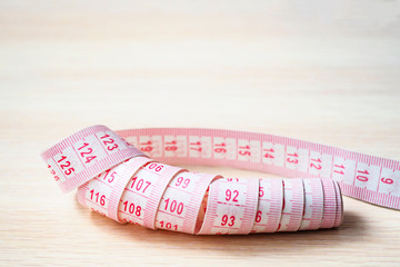 close up of measuring tape on a beige wooden background, selective focus, copy space