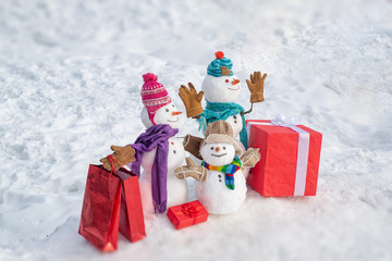 Delivery gifts. Snowman with gift in Christmas day. Snowman with a bag of gifts. Family Snowman on the background snowflakes. Winter background with snowflakes and snowman. Snowmen Family.