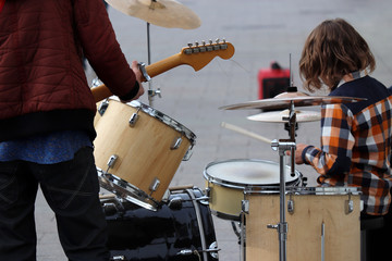 Street musicians play guitar and drums. Concert in a city, urban performers outdoor