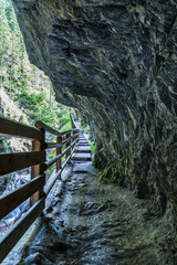 ein schmaler Weg mit Zaun führt durch eine Schlucht	