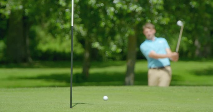 A Golfer plays a shot out of a sand trap / bunker on the the green