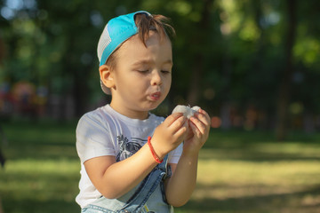 Little redheaded boy with cotton candy. Young boy standing and biting candy cotton on the park in a sunny day