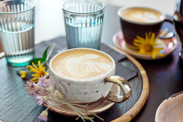 Obraz premium Different types of coffee in a cup on a dark table, two glasses with cold water and spring flowers on the table, top view
