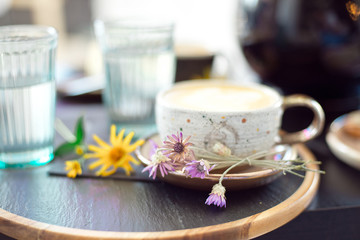 Two cups of cappuccino with latte art on a black table with two glasses of water in the background. View from above