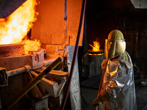 Industry, worker at furnace during melting copper, wearing a fire proximity suit