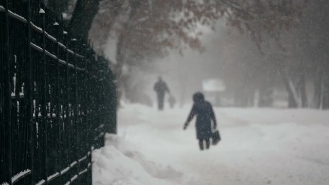 Urban people in the heavy snowstorm element and blizzard snowfall on the snowy street in the winter city 