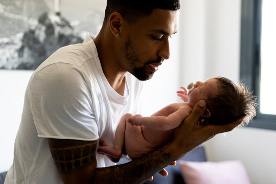 Side view of father holding newborn baby at home