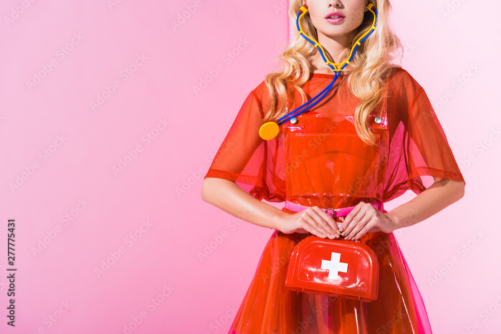 Wall mural cropped view of girl with first aid kit and stethoscope on pink, doll concept