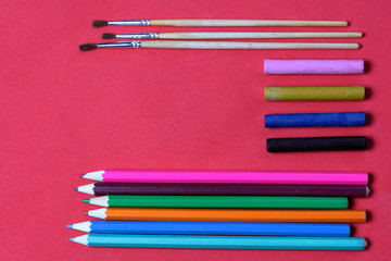 Fototapeta premium Accessories for sketching. Decomposed on the surface of coral color. School supplies.