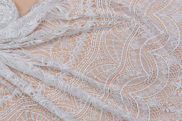 a background image of ivory-colored lace cloth. White lace on beige background.