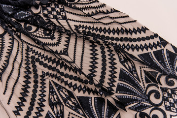 a background image of lace cloth. Black lace on beige background.