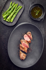Fried Iberian pork fillet sliced with blanched green asparagus and butter sauce with spice as top...