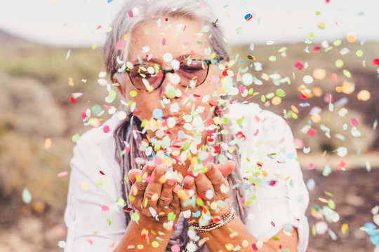 Senior woman blowing confetti outdoors