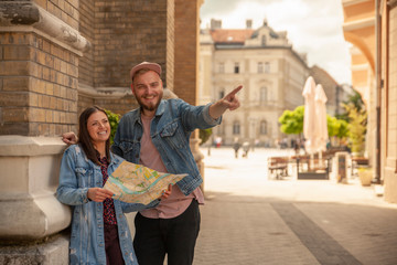 two friends, or couple, looking at a city map while one man is pointing finger. Location Novi Sad, Serbia.