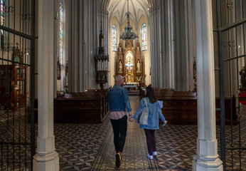 two young people, couple holding hands walking in a church indoors, walking in Aisle.
