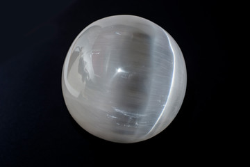 Beautiful white selenite sphere, cut mineral on black background, isolated