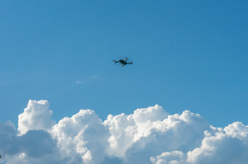 the quadcopter hovered above the clouds against the blue sky