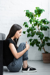 scared girl suffering from panic attack while sitting on floor at home
