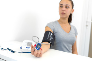 young beautiful girl measures the pulse and blood pressure at the reception of a therapist