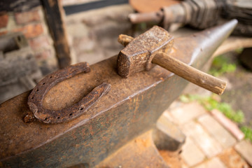 Tools in an old blacksmith's workshop. Horseshoe and hammer on a large anvil.
