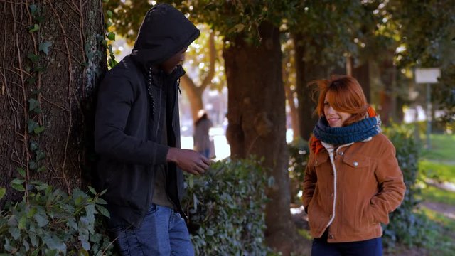 Black african dealer selling dose to young drug addicted woman in the park