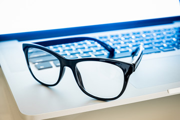 Computer goggles on a laptop, close-up view. Blue light blockers resting on computer keyboard, eye...
