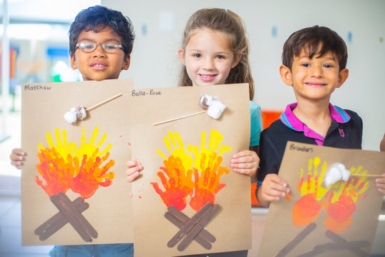 Portrait of smiling children presenting images of fire in kindergarten