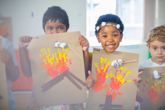 Portrait of smiling children presenting images of fire in kindergarten