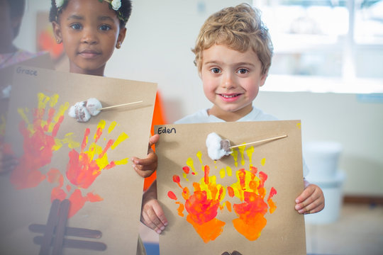 Portrait of smiling children presenting images of fire in kindergarten
