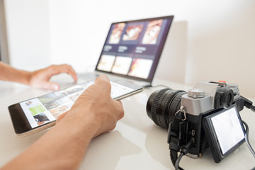 Managing digital images on a computer. Human hands hold a tablet to organise or import images from...