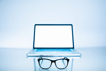 Computer eyeglasses in front of a laptop, close-up view. Blue light blockers and laptop in bright background, eye fatique problem concept