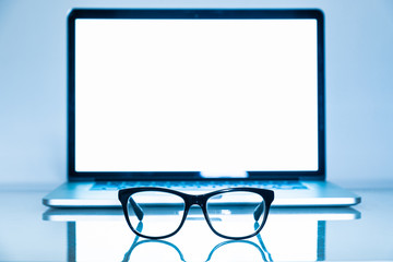 Computer eyeglasses in front of a laptop, close-up view. Blue light blockers and laptop in bright...