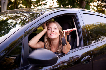 Happy young woman with keys in auto.